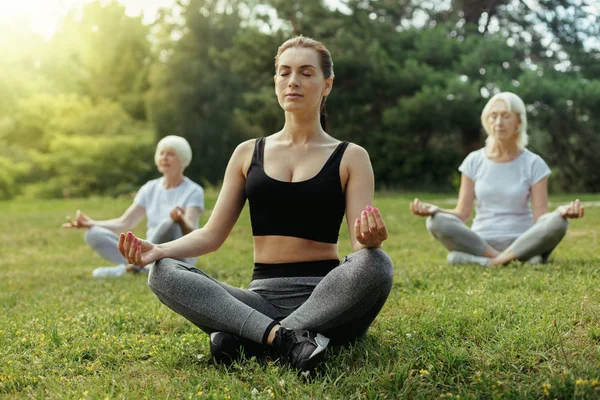 Young coach practicing yoga with senior ladies — Stock Photo, Image