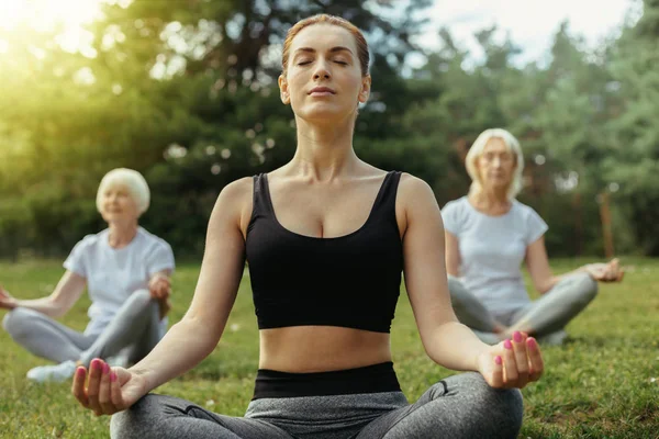 Mulher concentrada ensinando pessoas aposentadas ioga — Fotografia de Stock