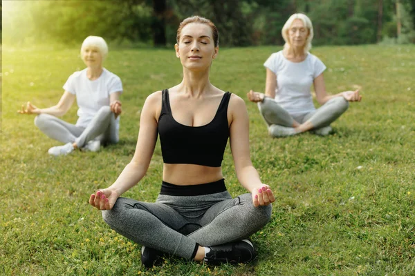 Jovencita mediadora durante la práctica de yoga con personas mayores — Foto de Stock