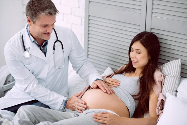 Médico bom positivo olhando para a barriga — Fotografia de Stock