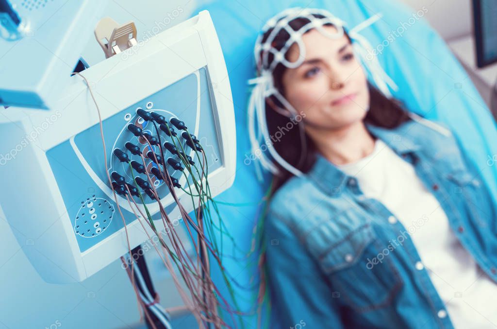 Young lady undergoing electroencephalography analysis at laboratory