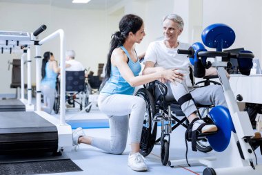 Bir rehabilitasyon merkezinde bir tekerlekli sandalye eğitim gülümseyen adam