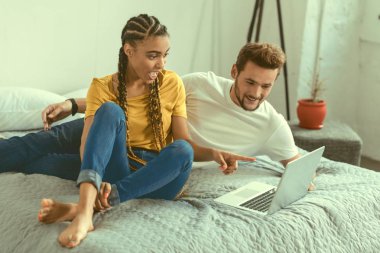 Sürpriz ile laptop doğru işaret eden duygusal genç bayan