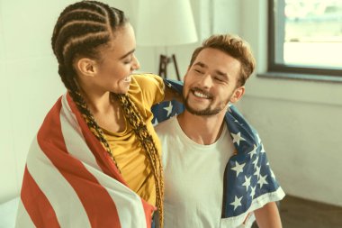 Kucaklayan ve gülümseyen ABD bayrağı ile seven çift