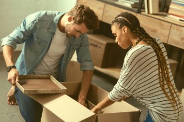 Concentrated young people packing stuff before moving clipart