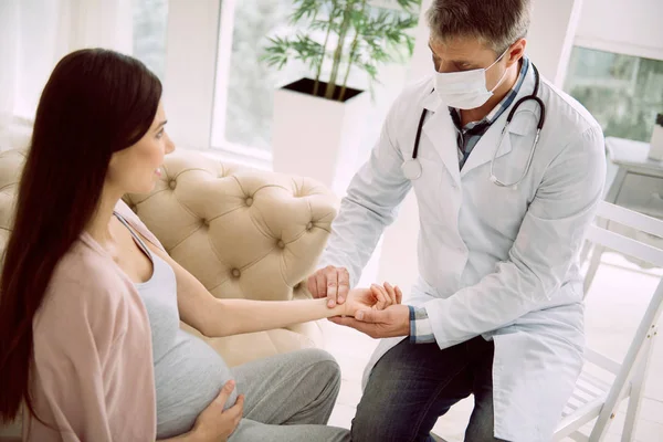 Serious male doctor holding his patients hand — Stock Photo, Image