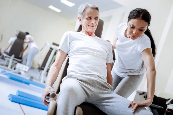 Allegro pensionato positivo sorridente mentre un medico professionista lo aiuta — Foto Stock