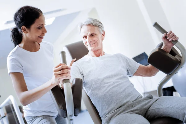 Freundlicher aufmerksamer Trainer, der einem fröhlichen Babyboomer Anweisungen gibt — Stockfoto