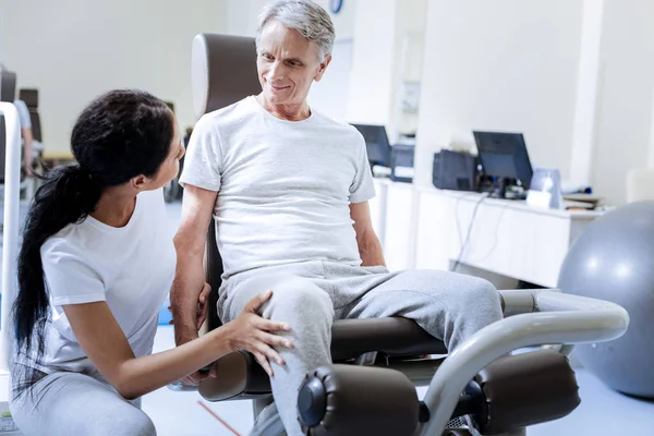 Slimme ervaren arts de knie van de patiënt aan te raken terwijl het helpen van hem — Stockfoto