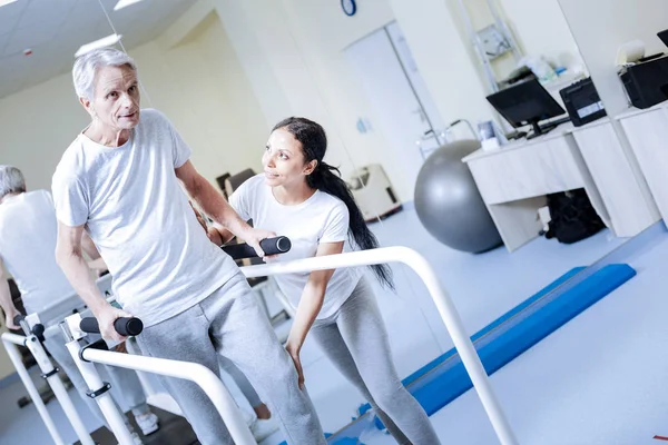 Hombre de edad dedicado tratando de caminar en una cinta de correr y buscando optimista —  Fotos de Stock