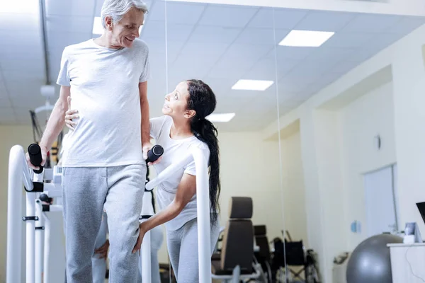 Positive assistant encouraging her patient to take steps on a treadmill — Stock Photo, Image