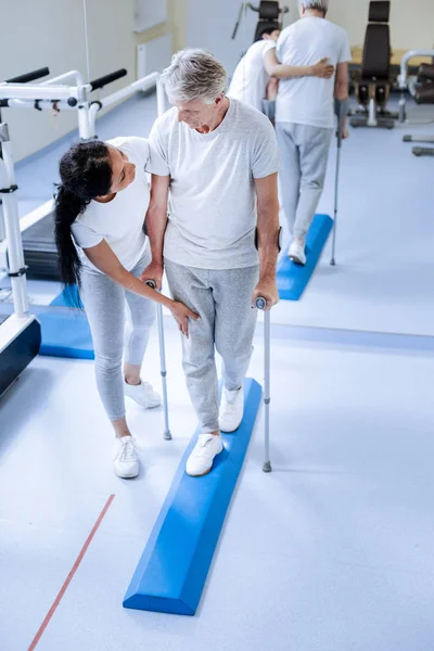 Travailleur médical attentif et serviable touchant la jambe blessée de sa patiente âgée — Photo