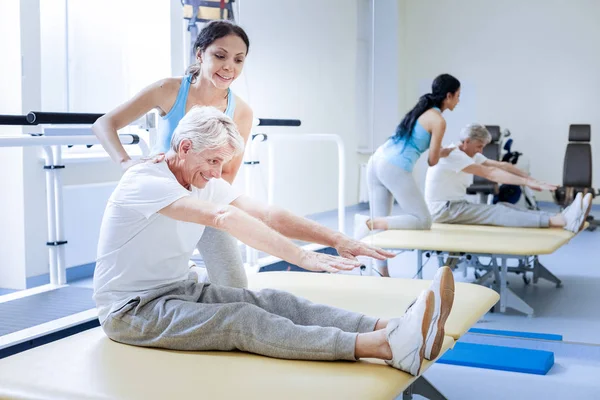 Positiver alter Mann versucht, seine Füße zu berühren und lächelt — Stockfoto