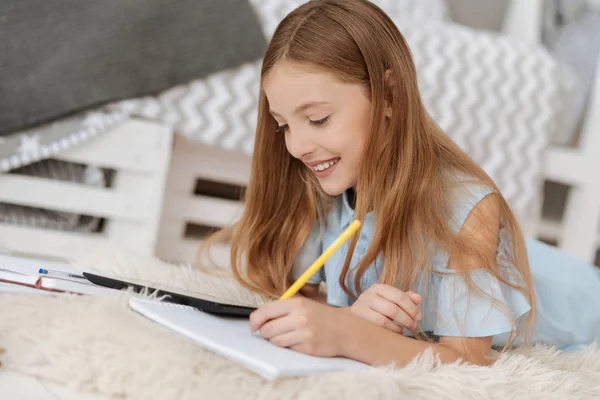 Hermosa chica escribiendo tarea en su copybook — Foto de Stock