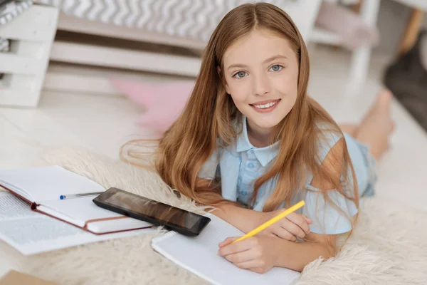 Pequeña hembra alegre haciendo notas importantes — Foto de Stock