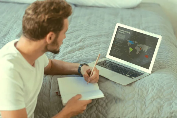 Сконцентрированный молодой человек, выполняющий домашнее задание за ноутбуком — стоковое фото