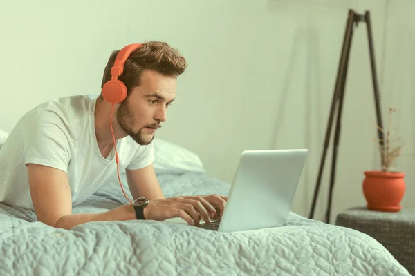 Concentrated guy wearing headphones working on laptop — Stock Photo, Image
