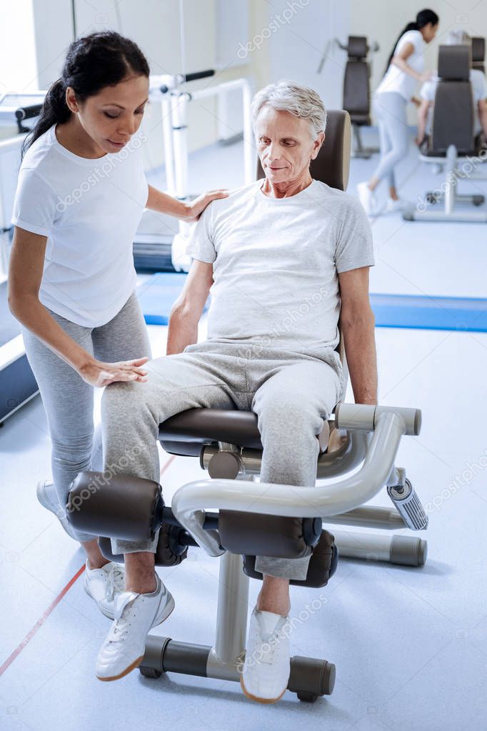 Serious concentrated injured man sitting on an exercise machine
