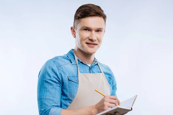 Fröhlicher netter Mann, der mit Bleistift schreibt — Stockfoto