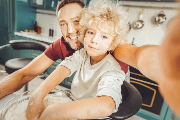 Dark-eyed riccio ragazzo cucina in cucina con bel padre — Foto Stock