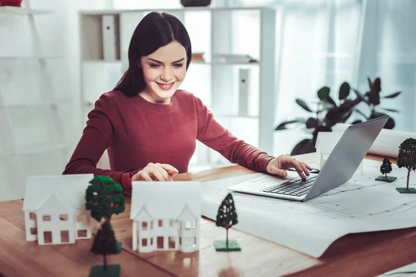 Fröhliche Brünette weiblich Blick auf Modell des Hauses — Stockfoto