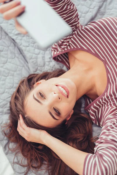 Vista superior de la chica descansada haciendo selfie en la cama — Foto de Stock