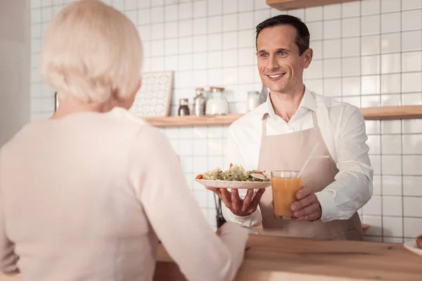 Positive friendly waiter holding food — Stock Photo, Image