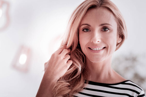 Красивая женщина трогает свои волосы и чувствует себя счастливой
