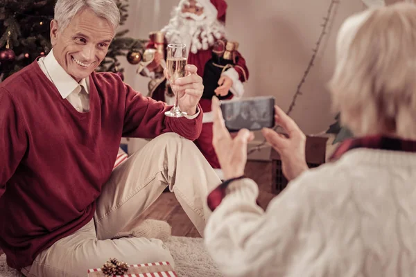 Feliz hombre sonriente sentado y sosteniendo un vaso . — Foto de Stock