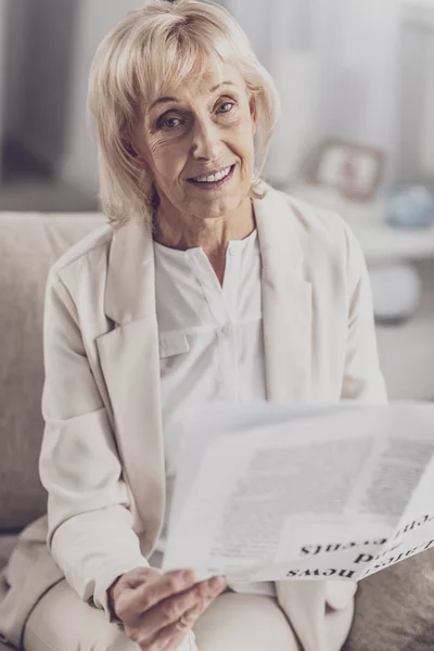 Äldre kvinna i snygg beige kostym som sitter i vardagsrummet — Stockfoto