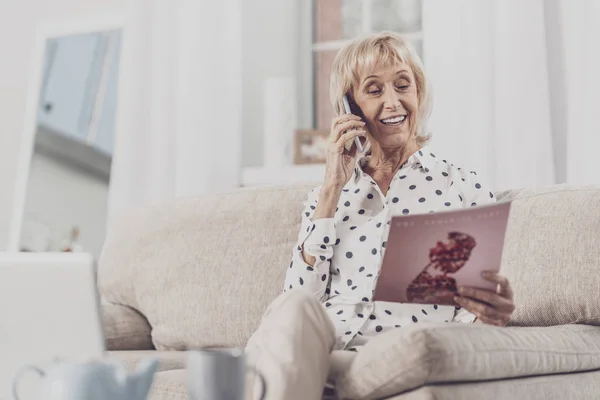 Elderly woman looking at fashion magazine cover