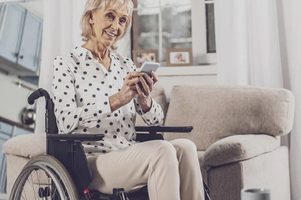Mujer de ojos azules sosteniendo su teléfono sentado en silla de ruedas — Foto de Stock