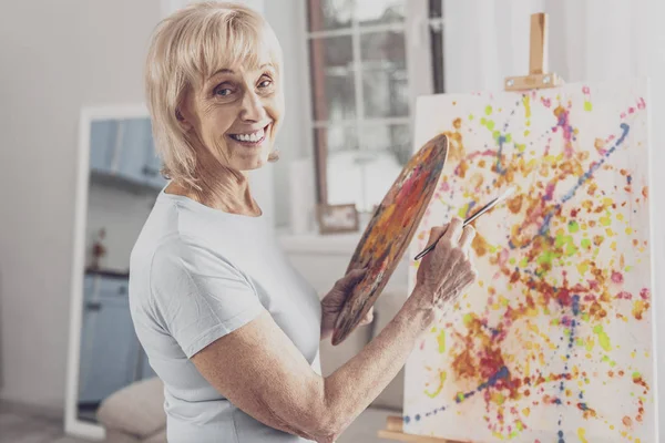 Smiling woman with facial wrinkles working with painting brush — Stock Photo, Image
