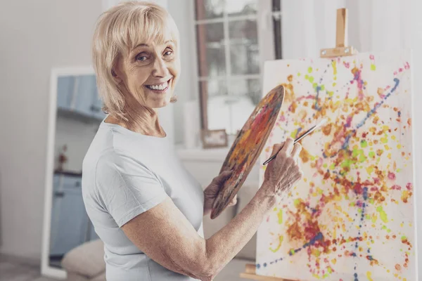 Mulher sorridente com rugas faciais trabalhando com pincel de pintura — Fotografia de Stock