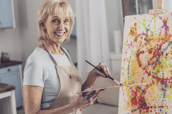 Ältere Frau mit Schürze zeichnet kreatives Bild — Stockfoto