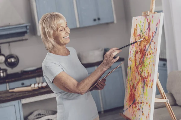 Strahlende Frau mit Malerpinsel in der Küche — Stockfoto