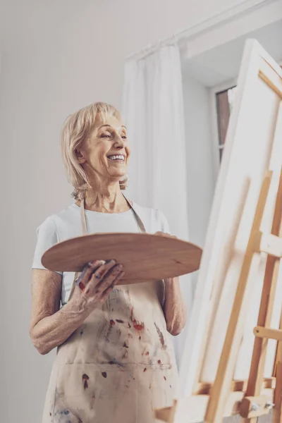 Blonde-haired smiling woman in apron drawing portrait — Stock Photo, Image