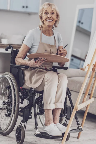 Καλλιτέχνης που κάθεται σε αναπηρικό καροτσάκι, κρατώντας την παλέτα χρωμάτων για την κατάρτιση — Φωτογραφία Αρχείου