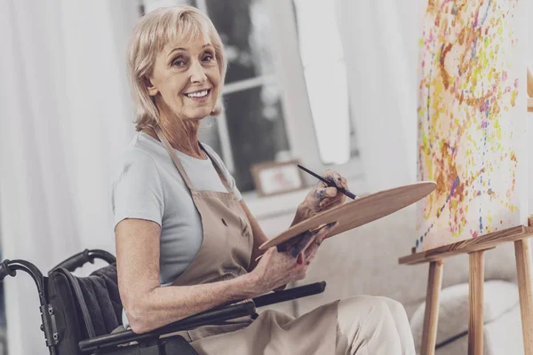 Artist sitting in wheelchair drawing colorful canvas — Stock Photo, Image