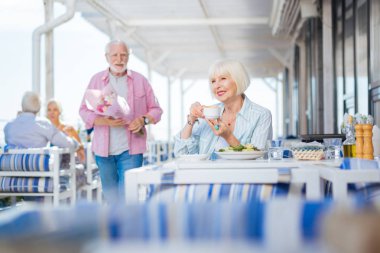 Bir fincan kapuçino tutan memnun güzel kadın