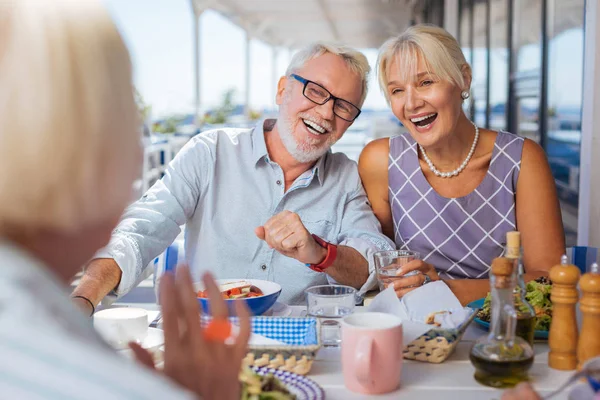 Fröhliches glückliches Paar, das über Witze ihrer Freunde lacht — Stockfoto