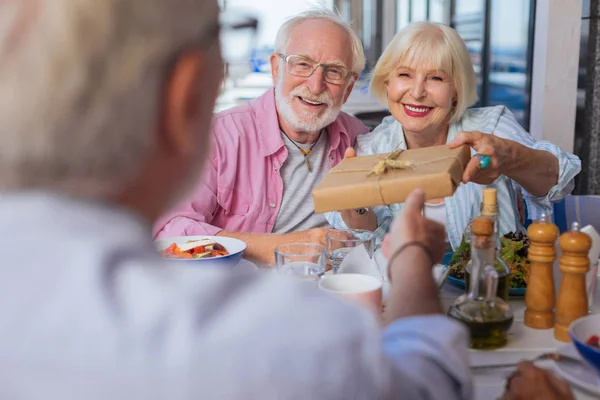 Alegre feliz casal dando um presente para seus amigos — Fotografia de Stock