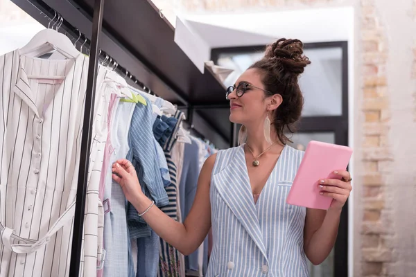 Asistente de tienda femenina feliz con respecto a la nueva colección — Foto de Stock