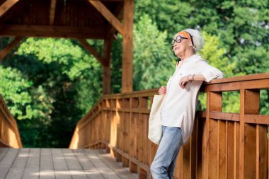 Köprüde duran ve kocası için bekleyen rahat yaşlı kadın