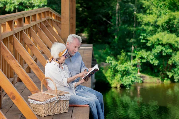 Sonriendo pareja de personas mayores inclinados el uno al otro y mirando el cuaderno — Foto de Stock
