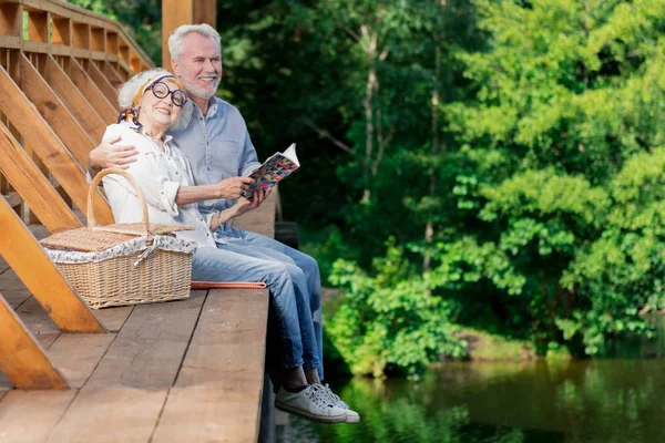 Krásný věku pár sedí na mostě a objímání — Stock fotografie