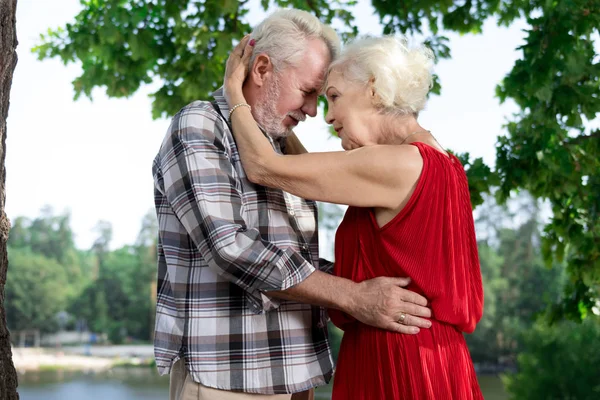 Pensionistas románticos poniendo sus cabezas juntas y mirándose entre sí — Foto de Stock