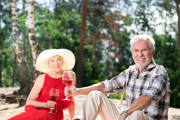 Bonito pensionista beber vinho enquanto se senta com sua bela esposa — Fotografia de Stock