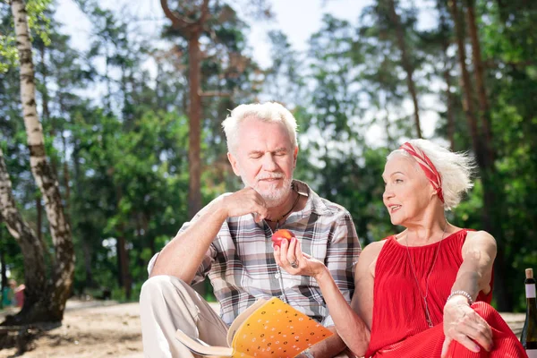 Druh důchodce nabízí ovoce svého manžela během jejich piknik — Stock fotografie