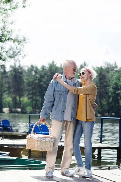 夫妇的退休者抱着篮子和拥抱在码头上 — 图库照片